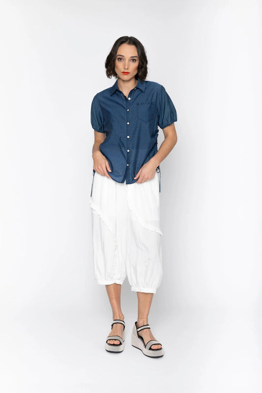 Woman wearing a blue shirt and white pants on a white background