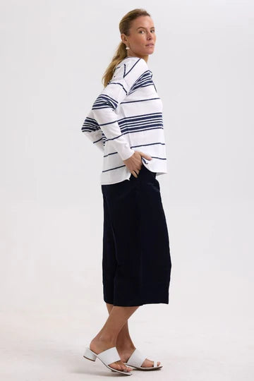 Woman wearing a white and blue striped shirt with a navy skirt on a white background
