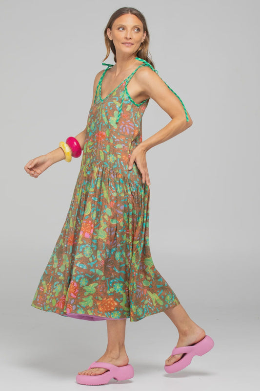 Woman wearing a colorful floral dress with pink sandals on a gray background