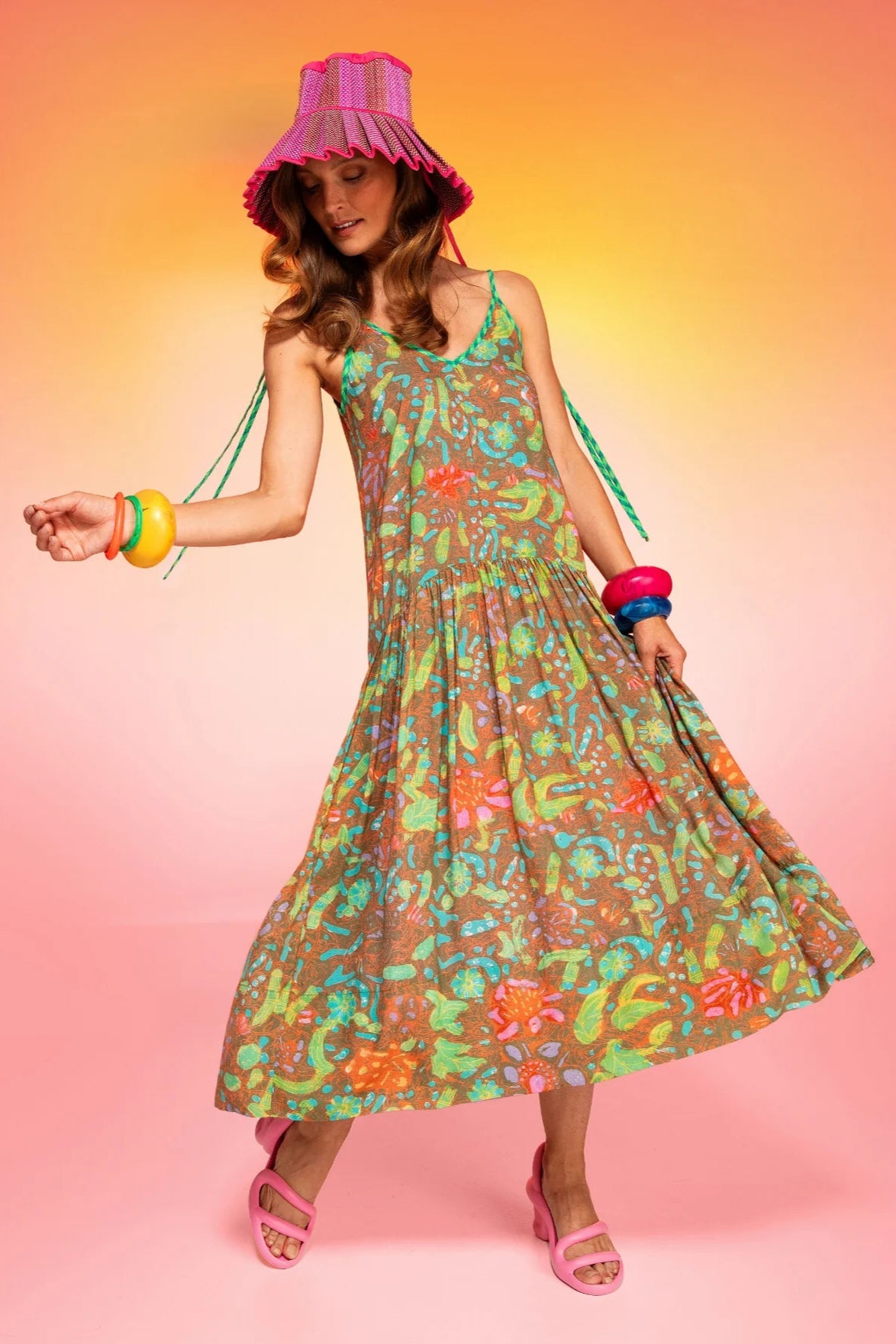 Woman wearing a colorful dress and hat against a gradient background