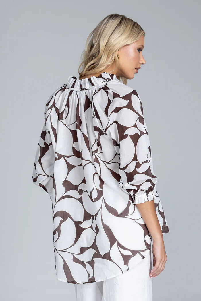 Woman wearing a floral patterned blouse against a gray background