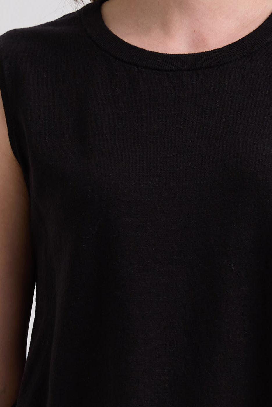 Black sleeveless top worn by a person, with a close-up view of the neckline.