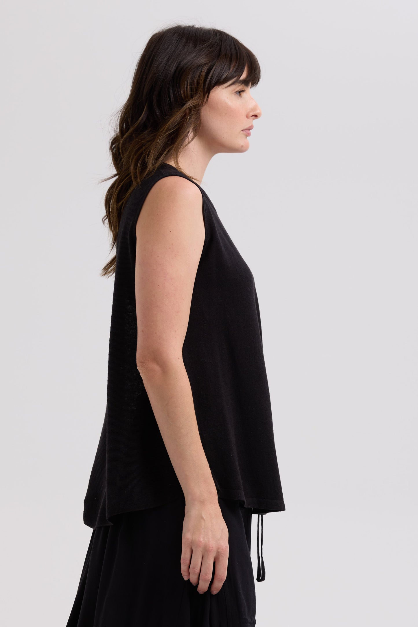 Woman wearing a black sleeveless top against a light gray background