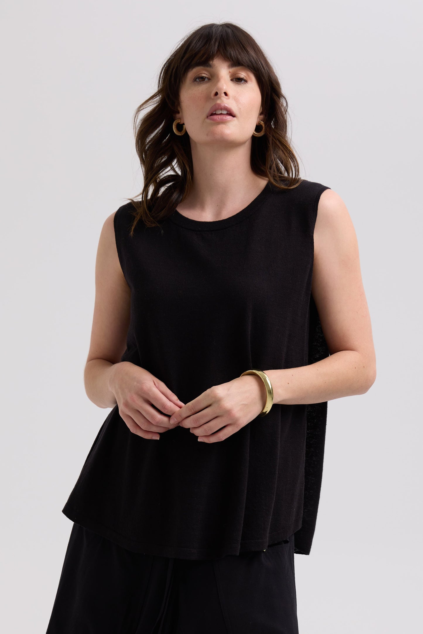 Woman wearing a black sleeveless top against a plain background