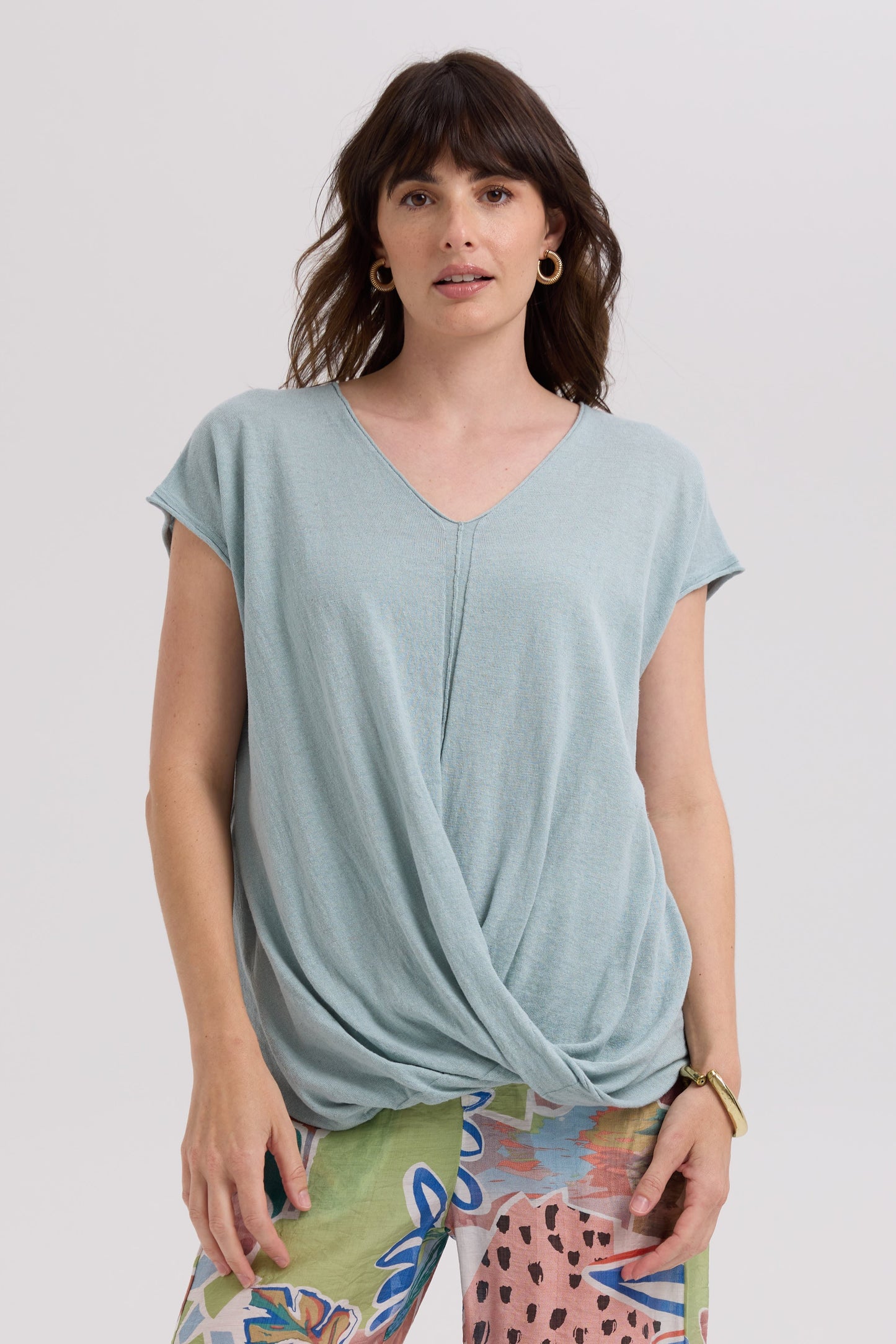 Woman wearing a light blue top with a knot detail on a white background