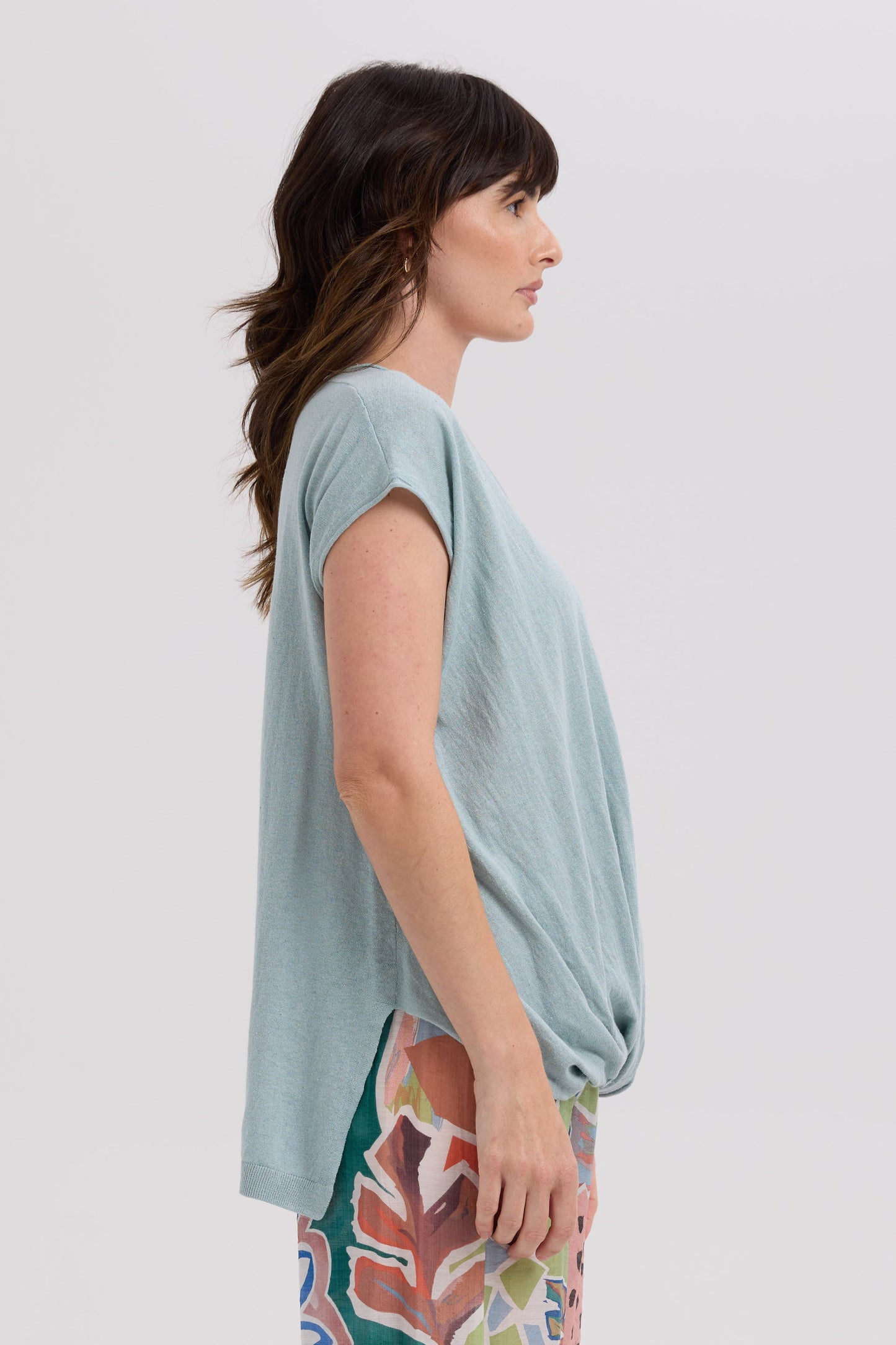 Woman wearing a light blue top and colorful pants on a white background