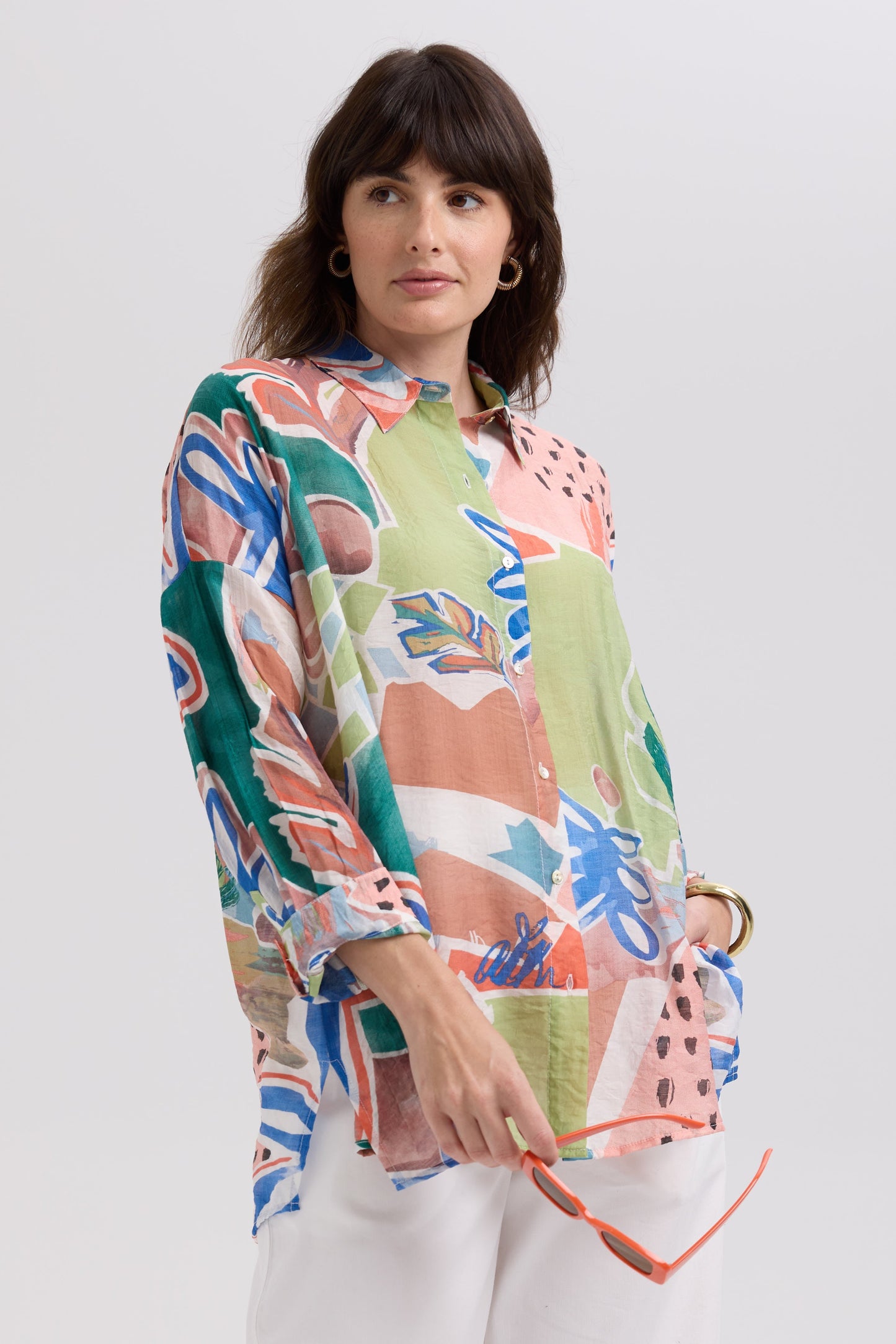 Woman wearing a colorful floral blouse against a white background
