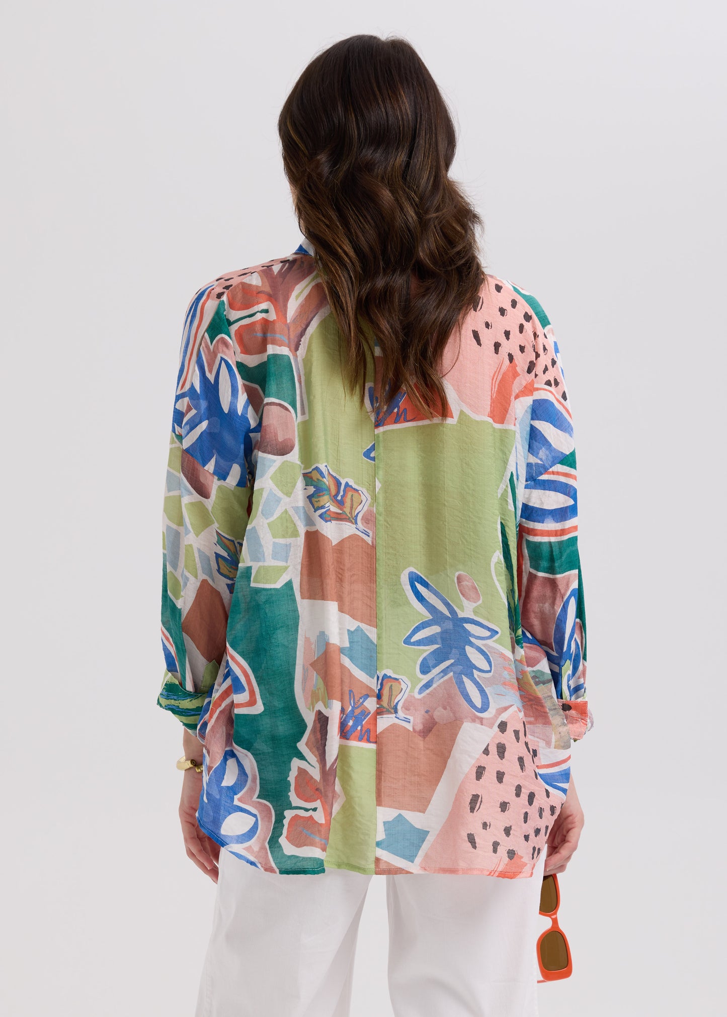 Woman wearing a colorful patterned top with a plain background