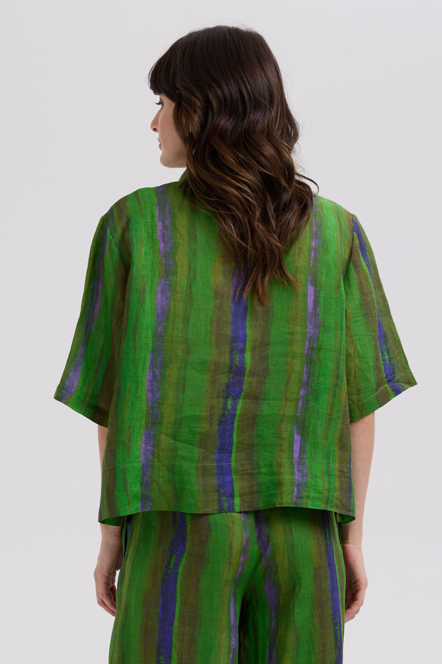 Woman wearing a green and purple striped outfit on a white background