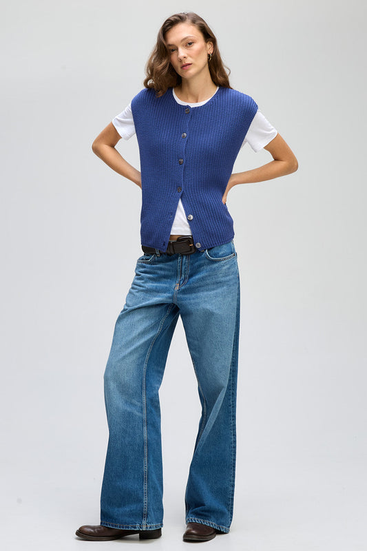 Person wearing a blue vest and jeans on a white background