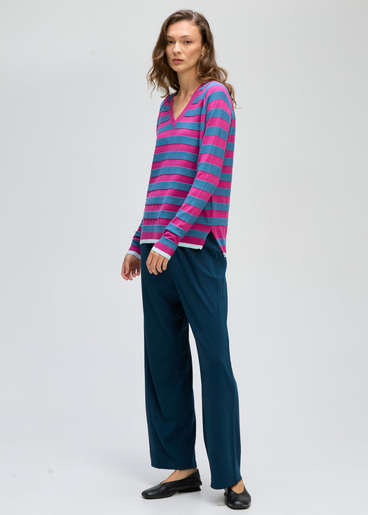 Woman wearing a striped long-sleeve top and dark pants on a white background