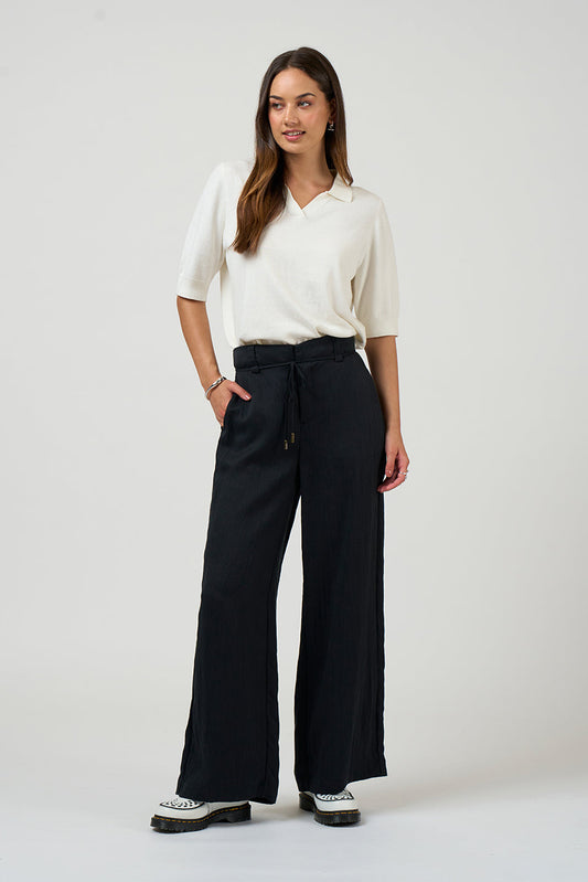 Woman wearing a white blouse and black wide-leg pants on a white background