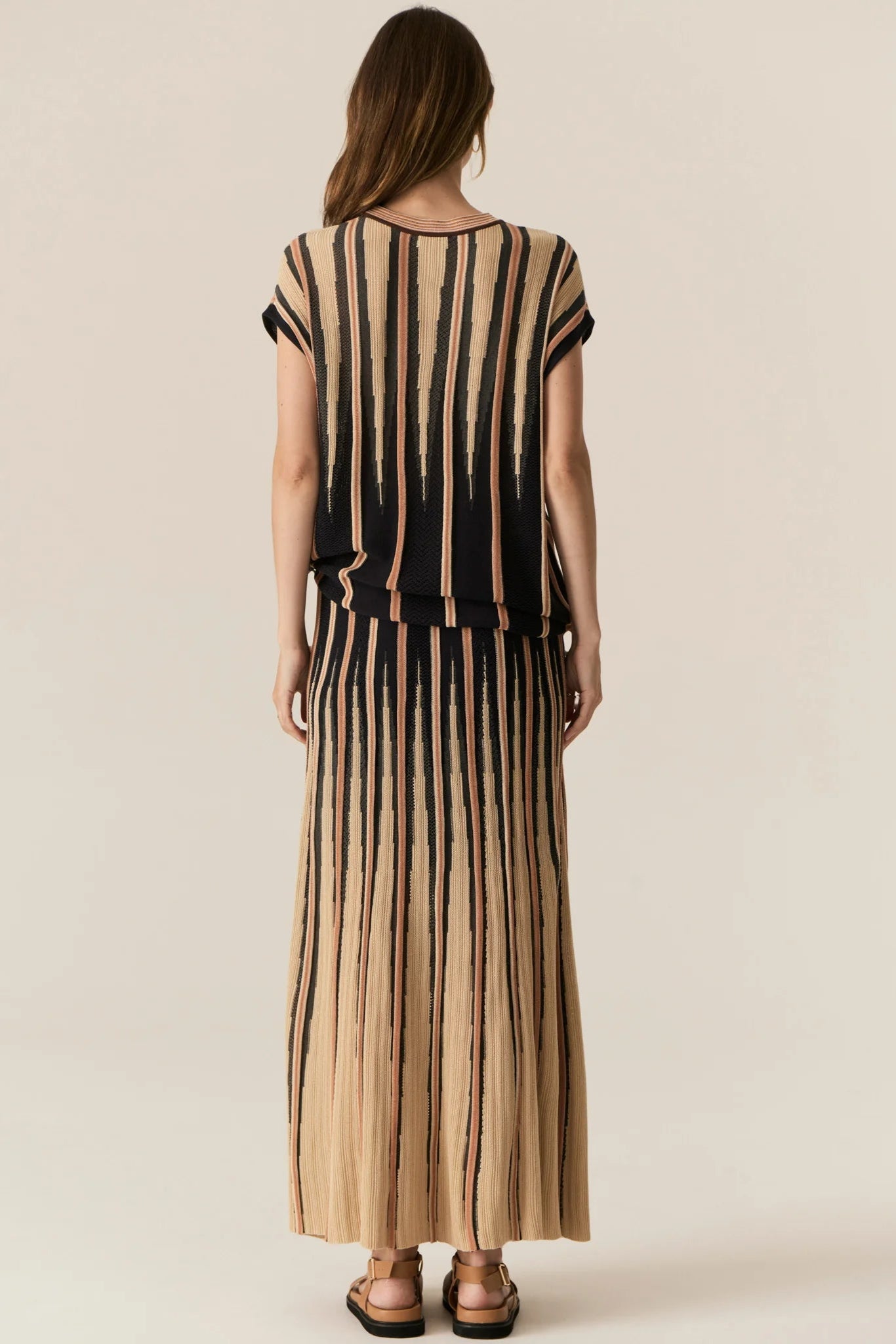 Woman wearing a black and beige striped dress on a plain background