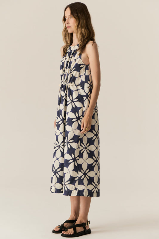 Woman wearing a sleeveless dress with a geometric pattern on a beige background