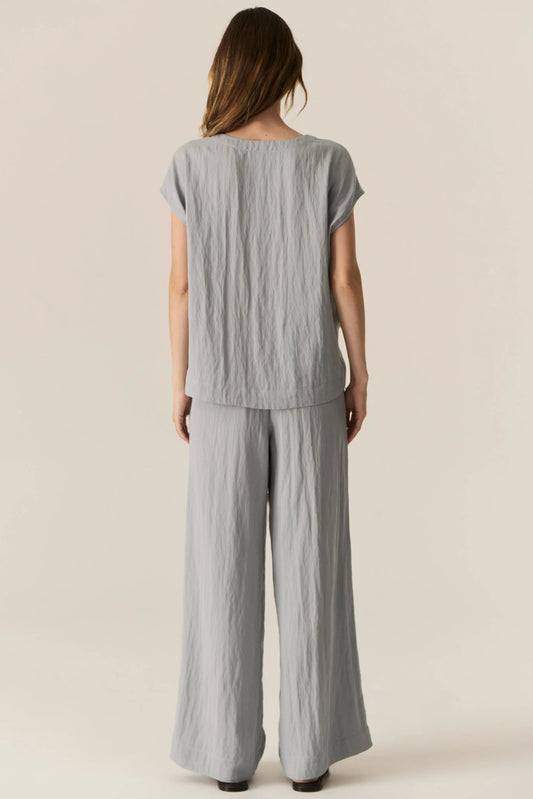 Woman wearing a gray textured outfit on a beige background