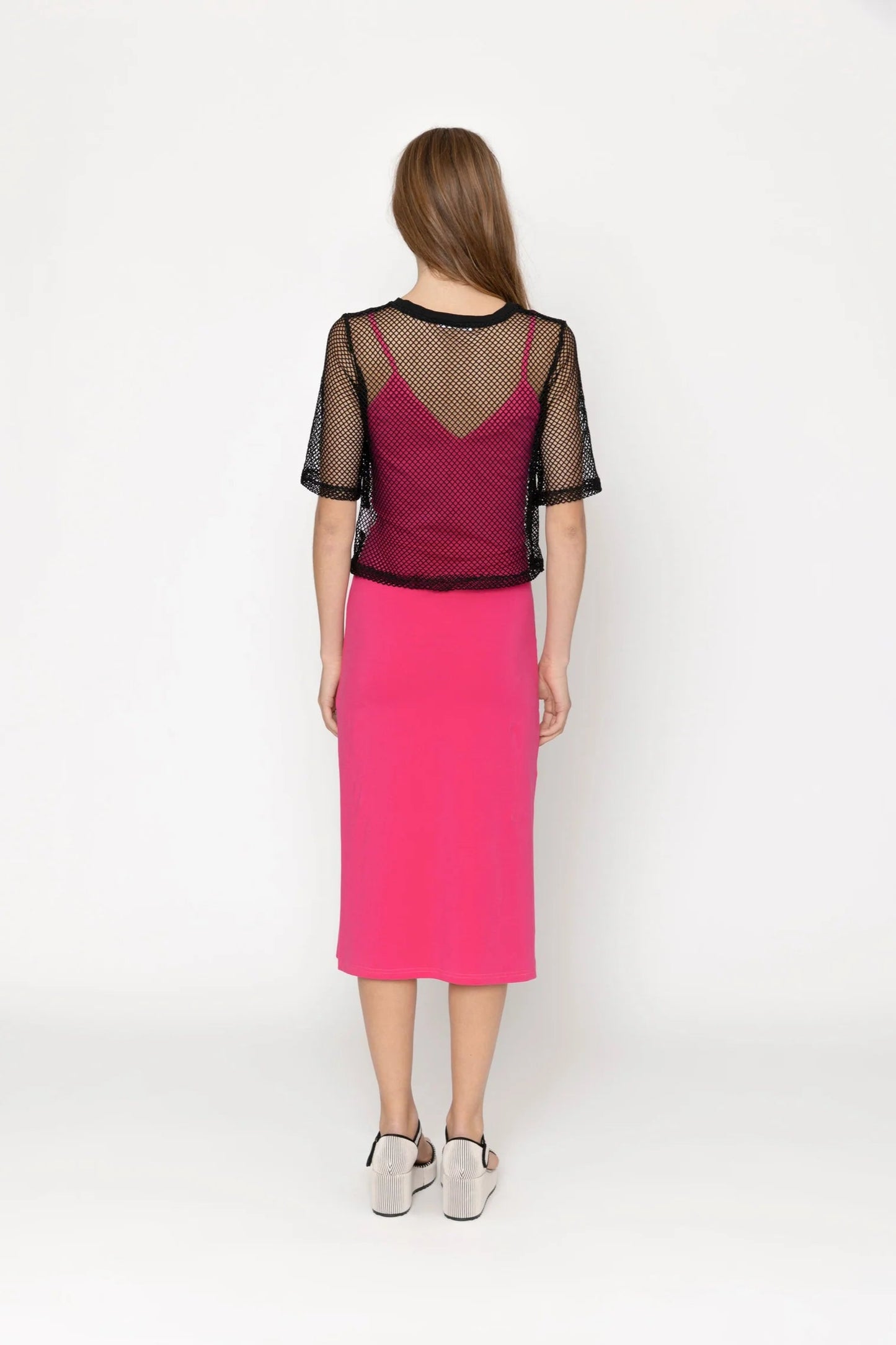 Woman wearing a pink dress with a sheer top on a white background