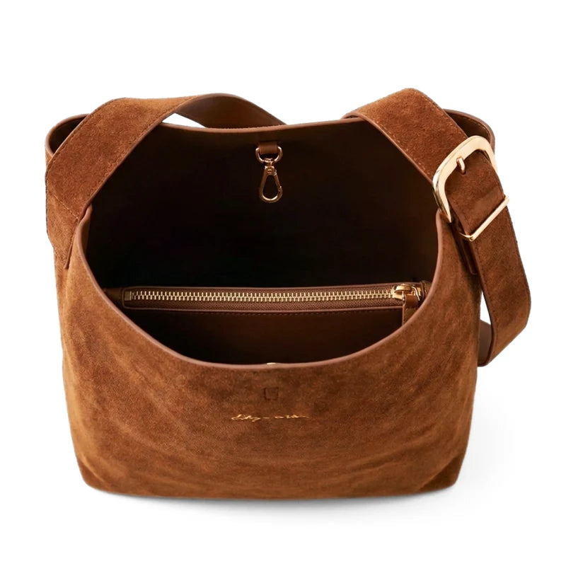 Brown suede handbag with gold zipper and hardware on a white background