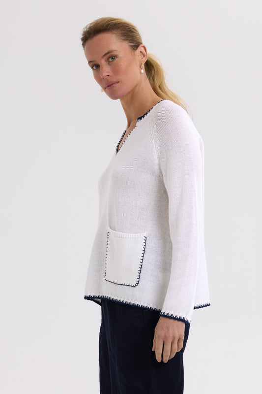 Woman wearing a white and navy patterned cardigan on a light gray background