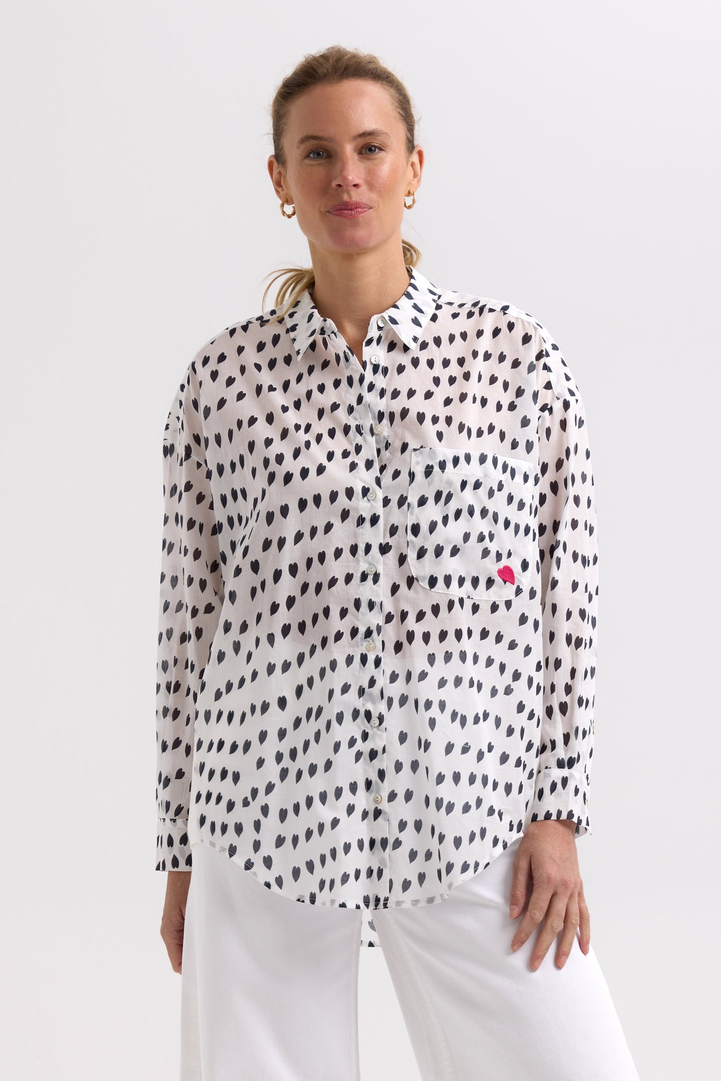 Woman wearing a white blouse with black pattern and red heart on a white background