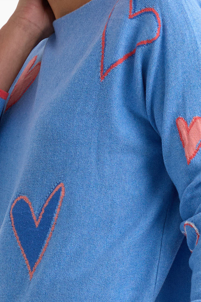 Blue sweater with red heart patterns on a person wearing it.