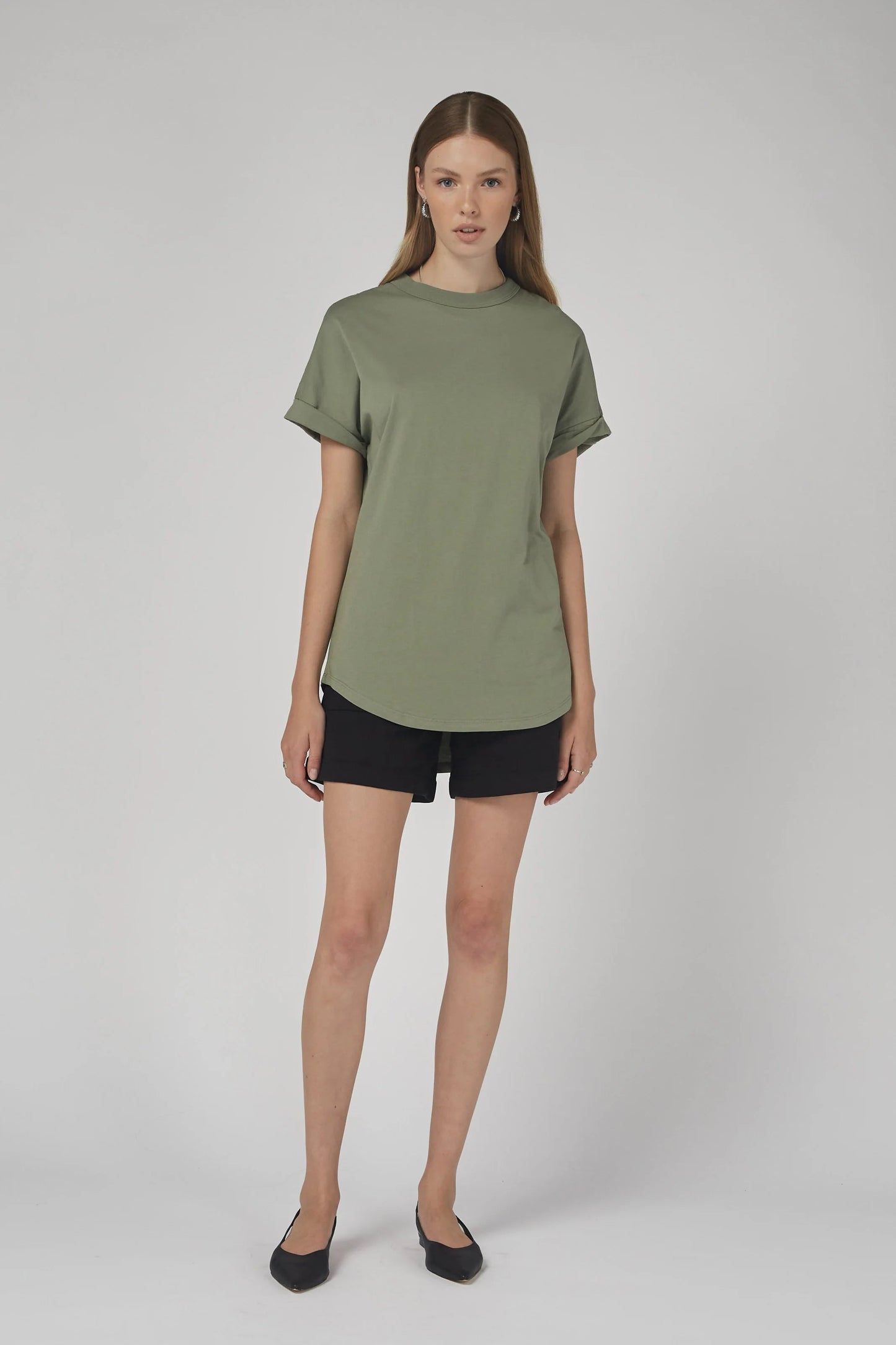 Woman wearing a green t-shirt and black shorts on a white background