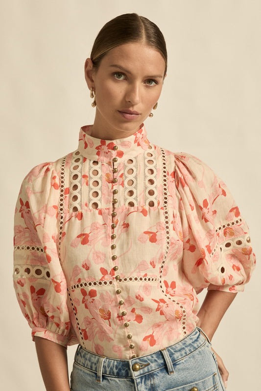 Woman wearing a floral blouse with puffed sleeves against a beige background