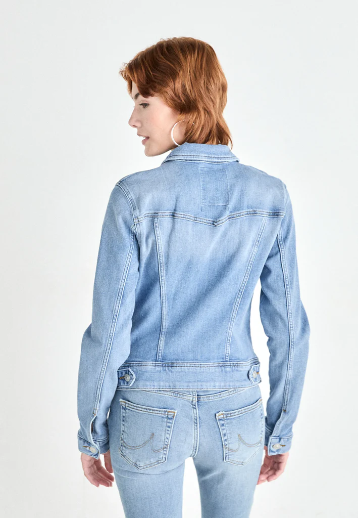 Woman wearing a light blue denim jacket and jeans on a white background
