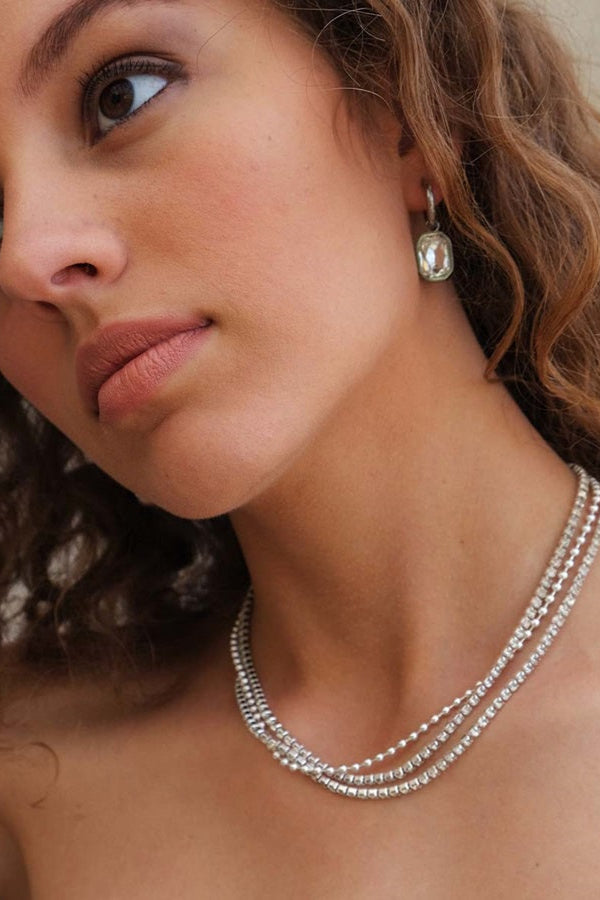 A person wearing a silver statement necklace with crystal embellishments.