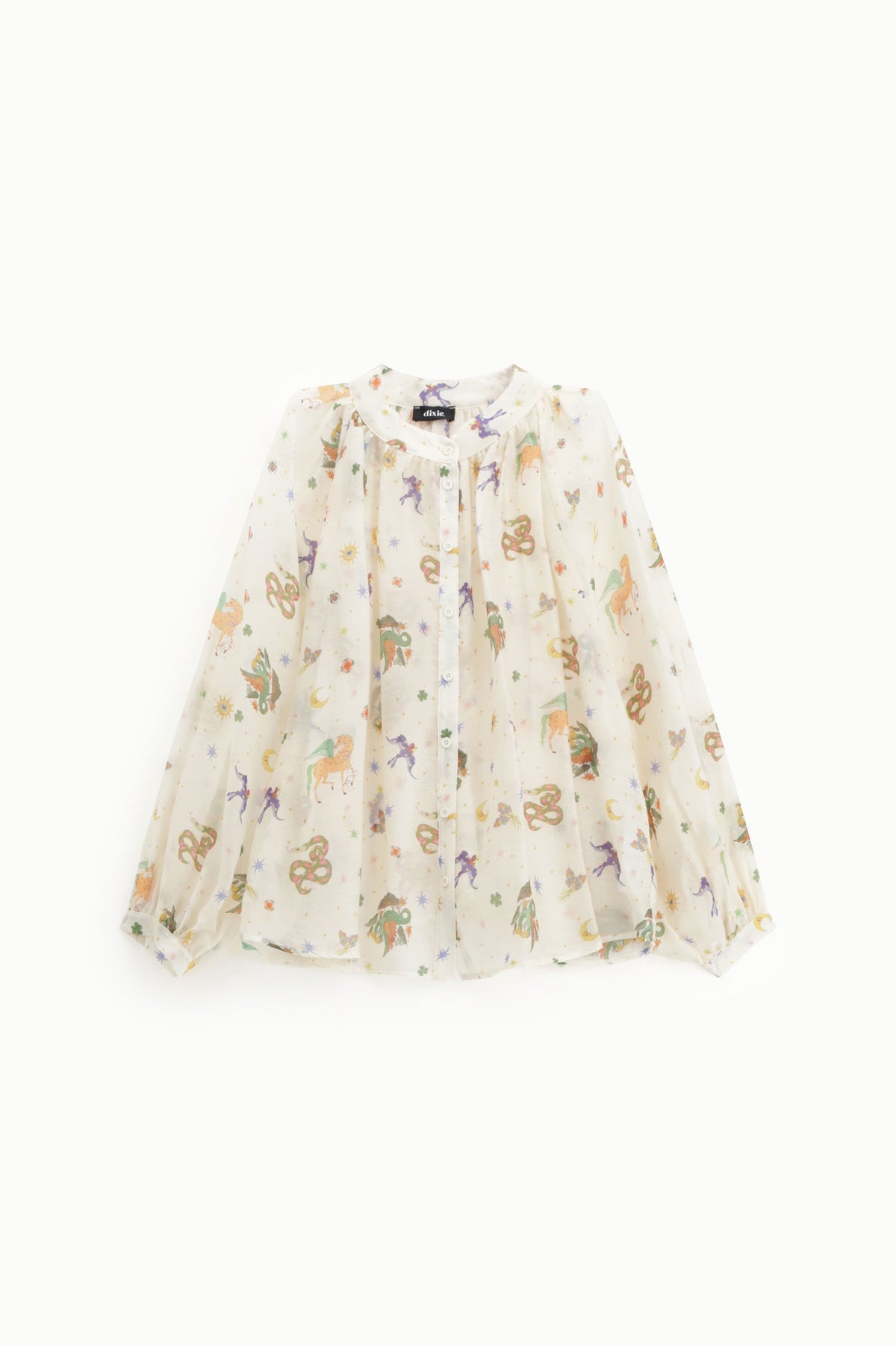 A long-sleeve, semi-sheer blouse in a warm cream or off-white color, decorated with a whimsical all-over print of colorful unicorns, stars, and moons. The blouse is displayed flat against a clean, solid white background.