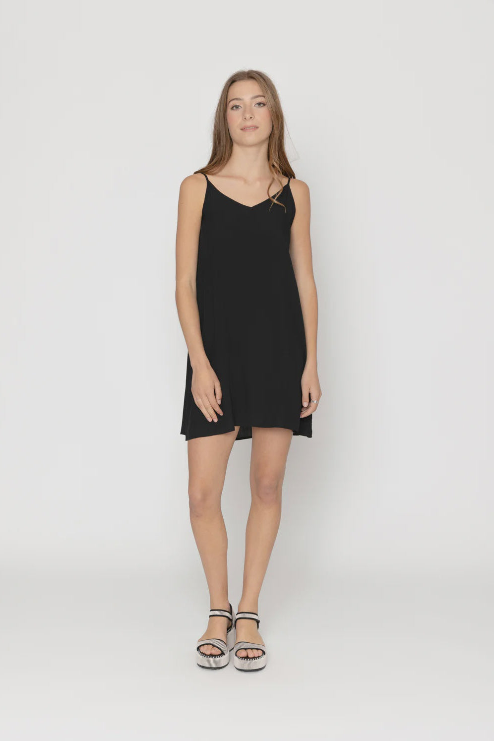 Woman wearing a black slip dress on a white background