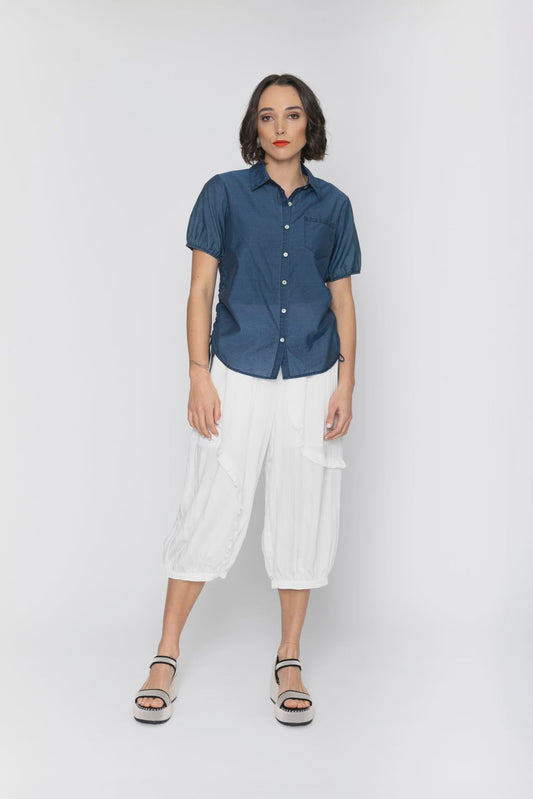Woman wearing a blue shirt and white pants on a white background