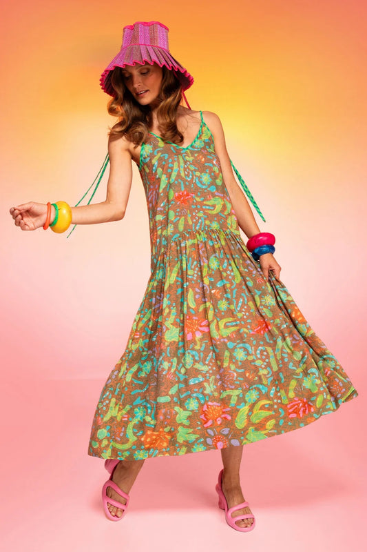 Woman wearing a colorful dress and hat against a gradient background