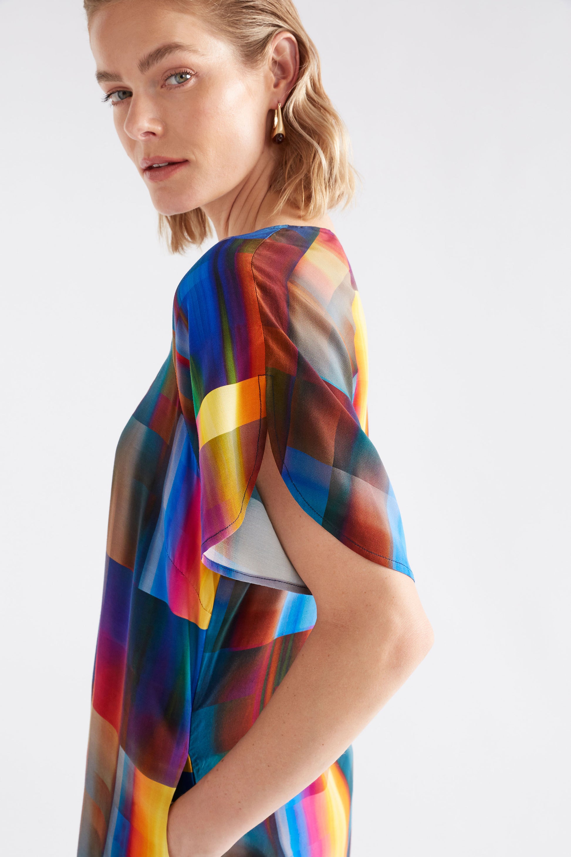 Woman wearing a colorful, patterned garment against a white background