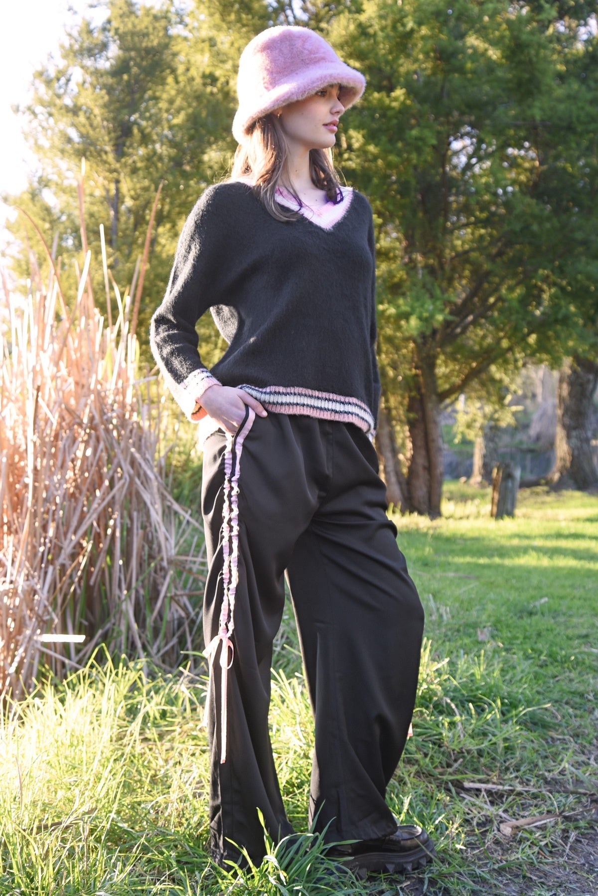 Person wearing a black outfit with a pink hat in a natural setting