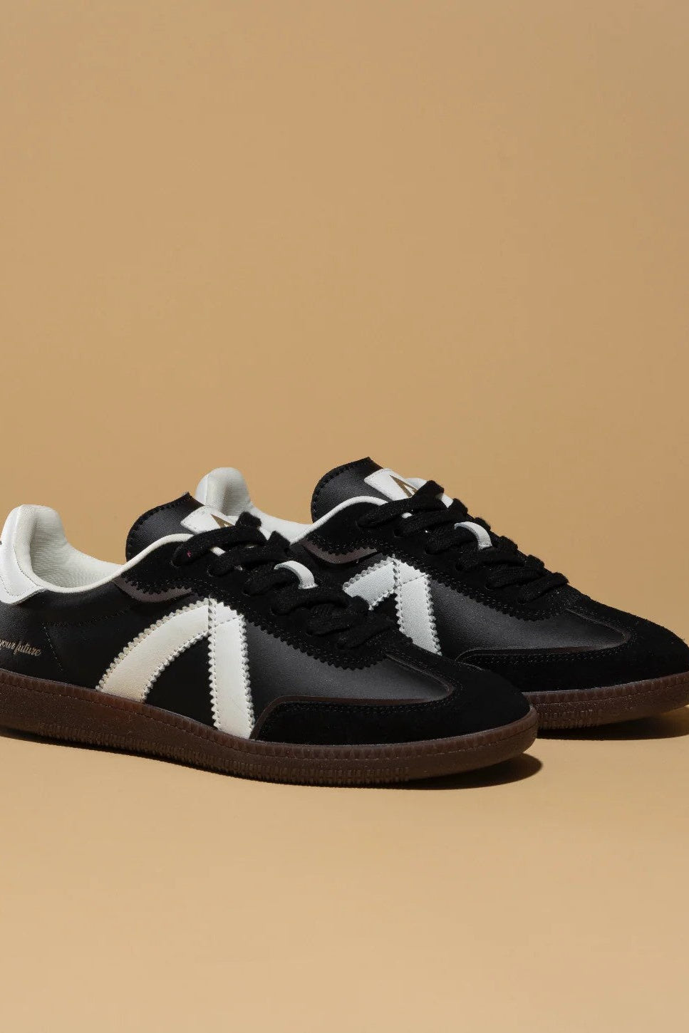 Black and white sneakers with a brand logo on a beige background