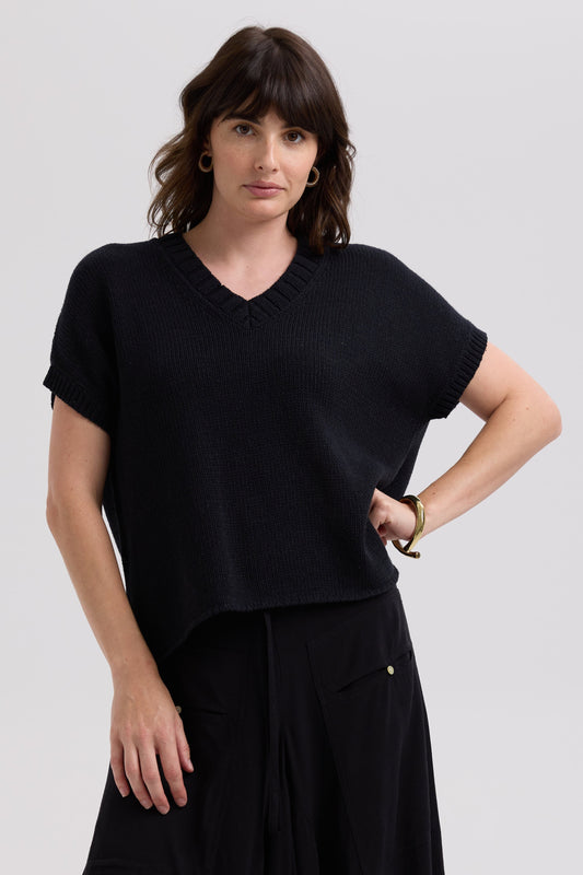 Woman wearing a black top and black pants on a light gray background