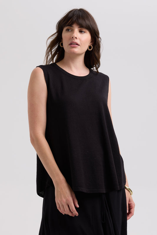 Woman wearing a black sleeveless top against a plain background