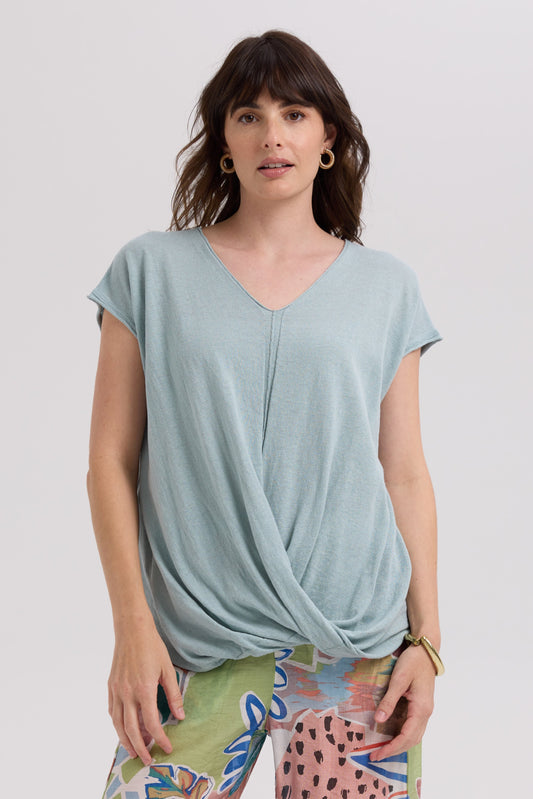 Woman wearing a light blue top with a knot detail on a white background