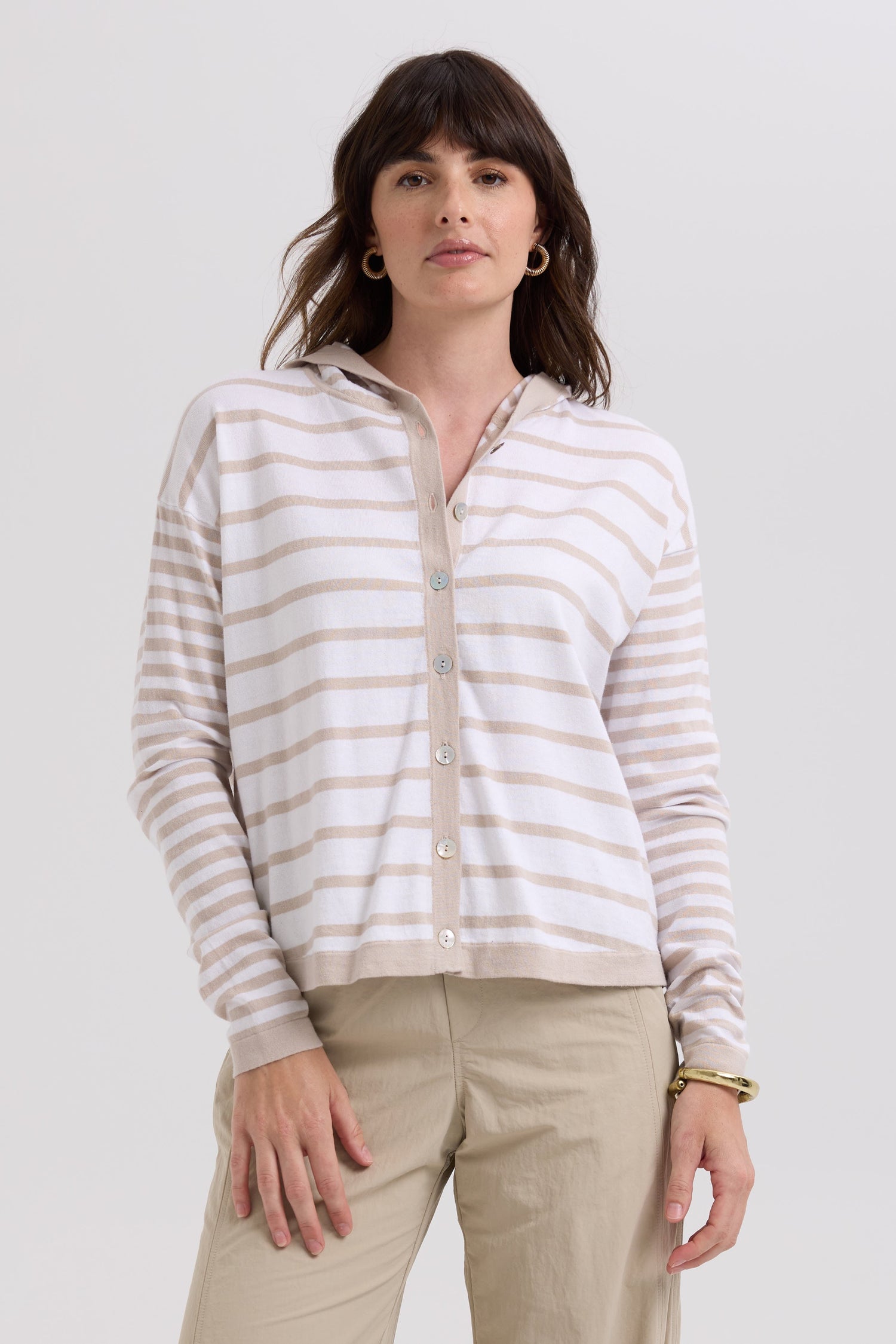 Woman wearing a striped shirt and beige pants on a white background