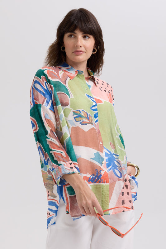 Woman wearing a colorful floral blouse against a white background