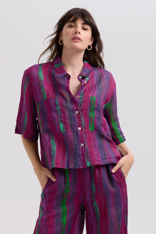 Woman wearing a purple and green patterned outfit on a white background