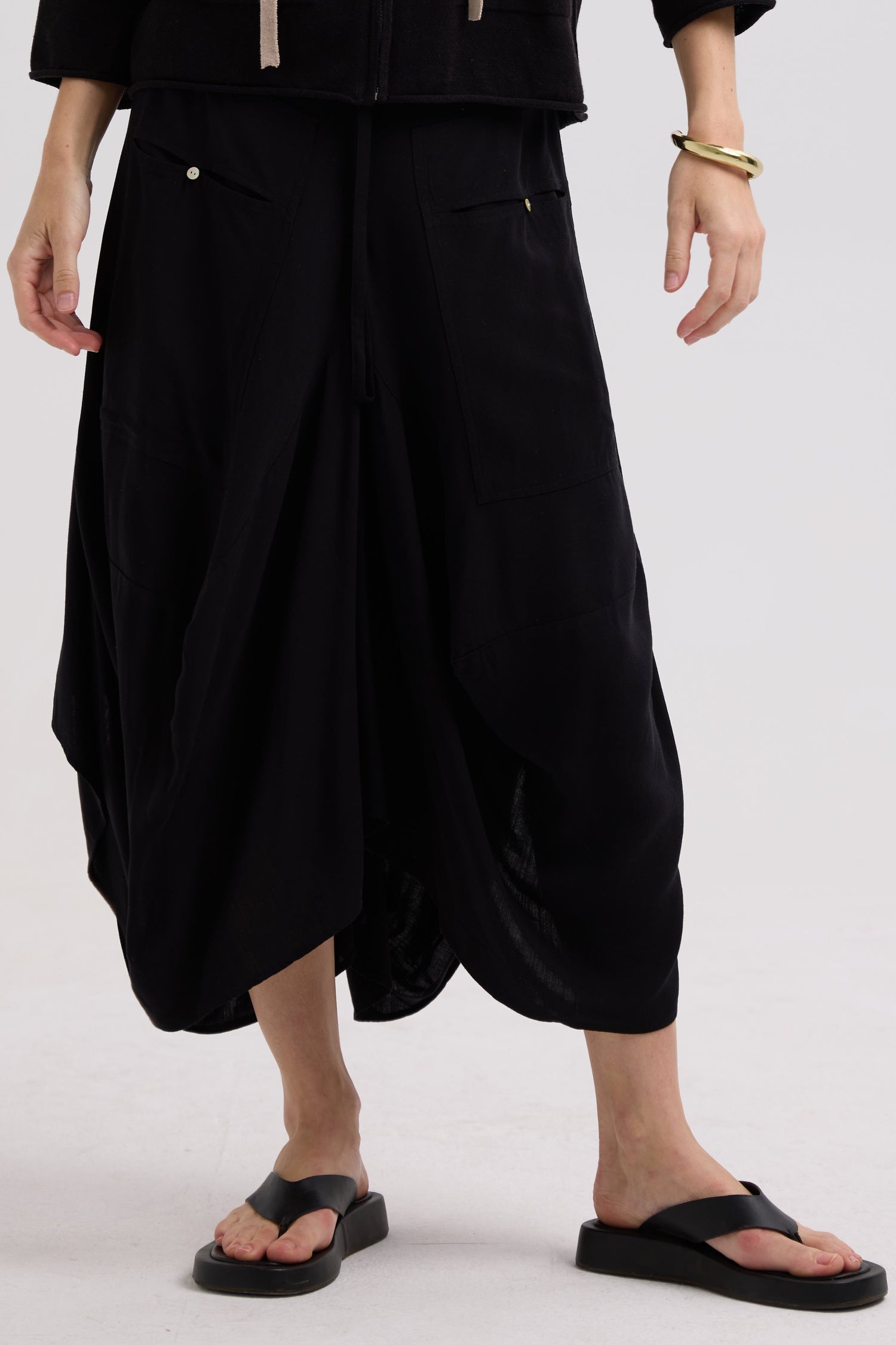 Person wearing black loose-fitting pants on a white background