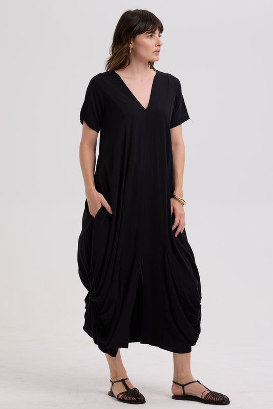 Woman wearing a black dress with a draped skirt on a white background