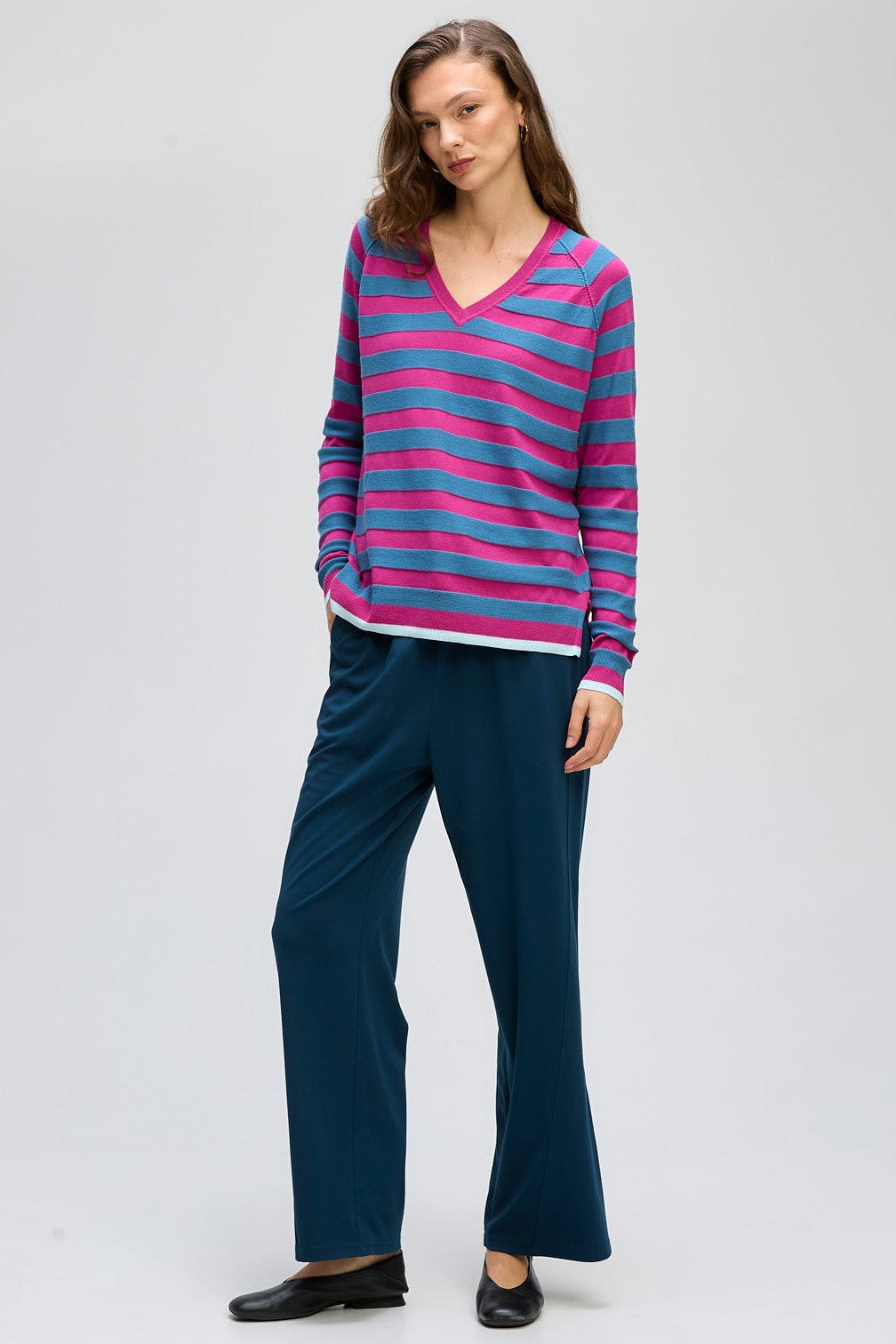 Woman wearing a striped sweater and dark pants on a white background