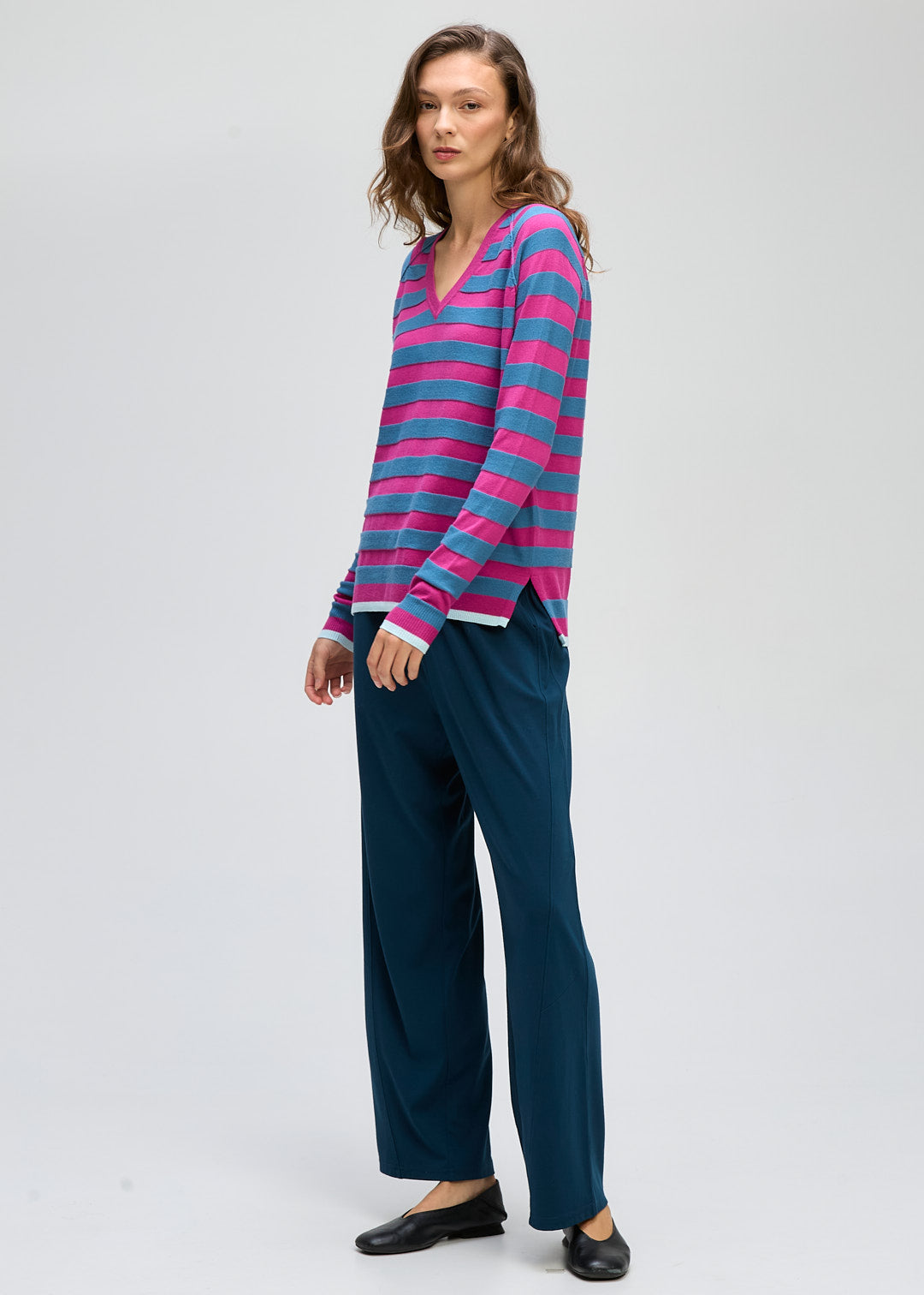 Woman wearing a striped long-sleeve top and dark pants on a white background