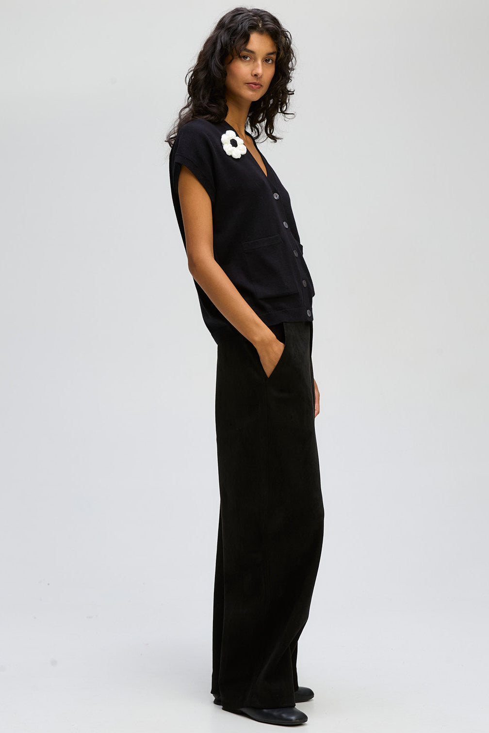 Woman wearing a black outfit with a white flower detail on a white background