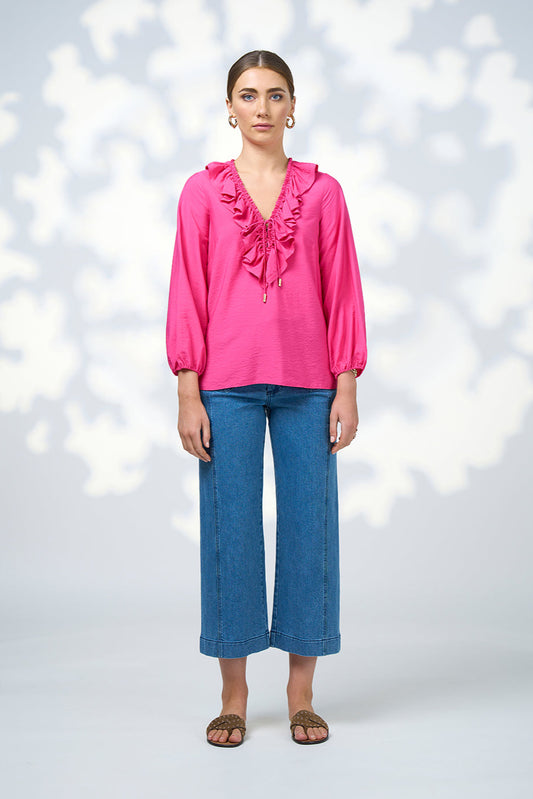 Woman wearing a pink blouse and blue jeans against a white background