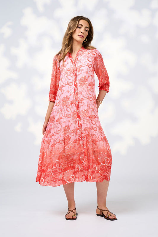 Woman wearing a coral floral dress against a white background