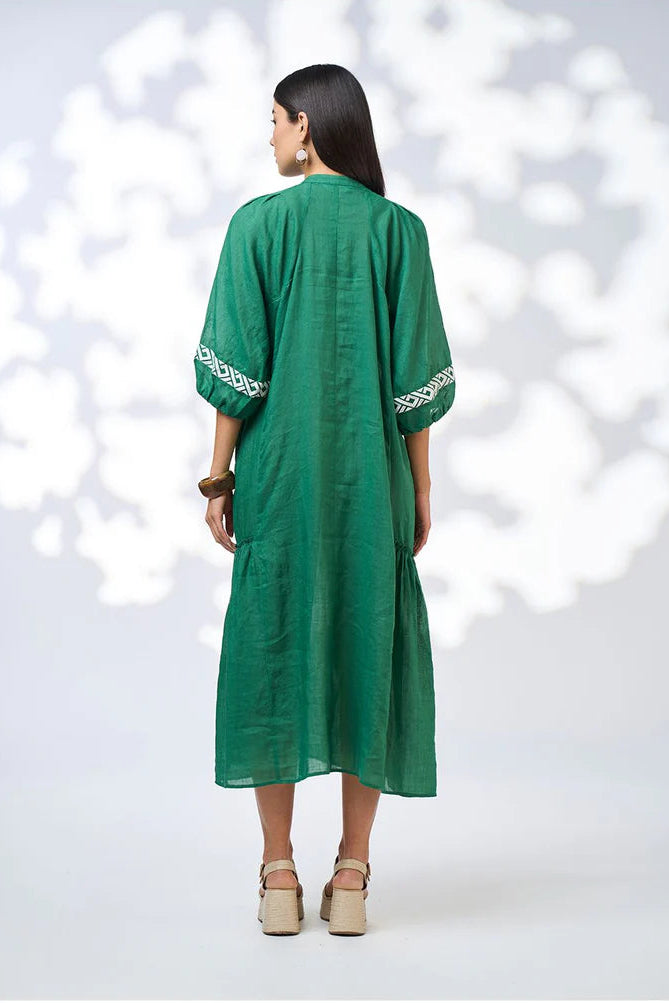 Woman wearing a green dress with white embroidery on a white background