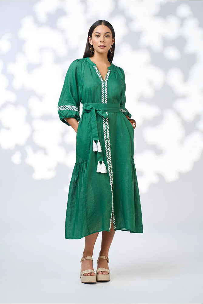 Woman wearing a green dress with white patterns on a white background